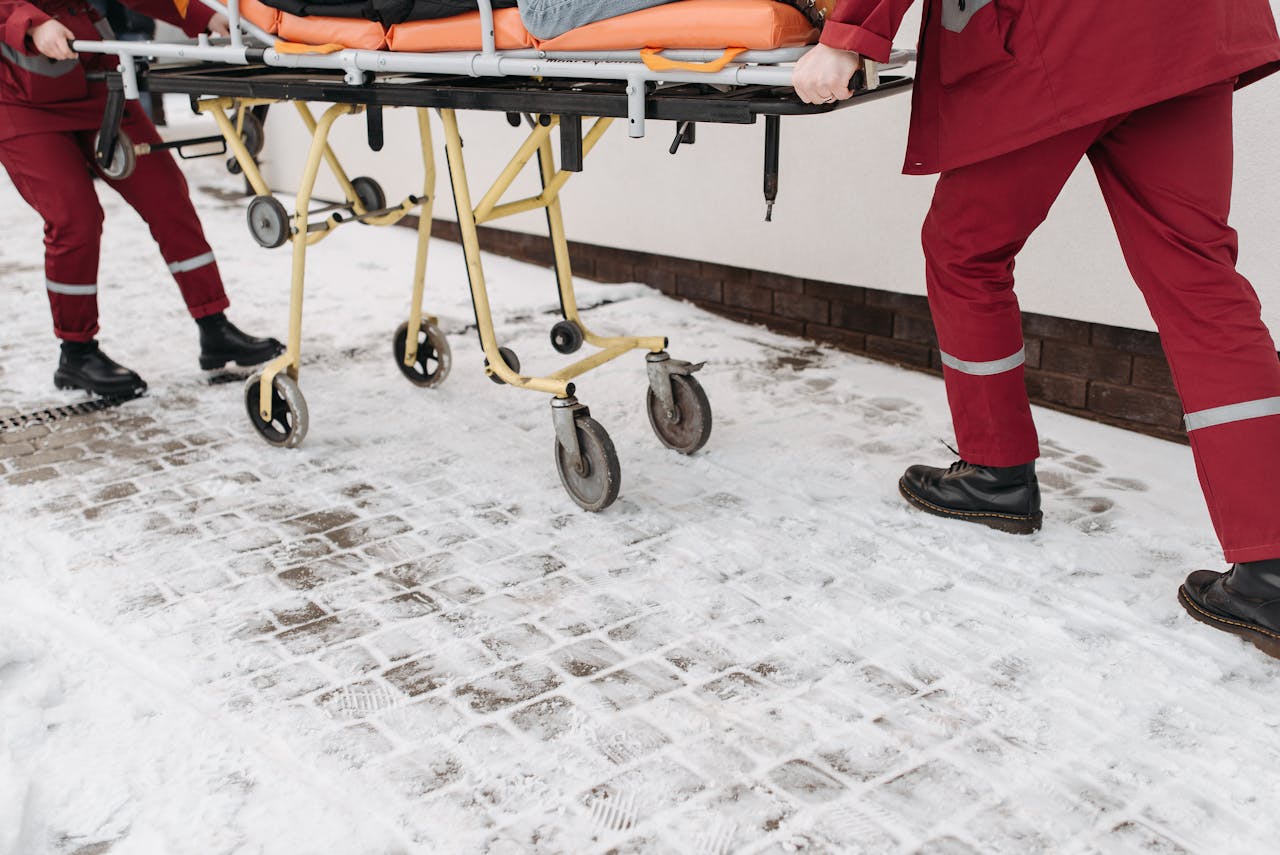 who-we-are Two paramedics moving a stretcher across a snow-covered surface outdoors, showcasing emergency response.